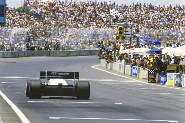 Keke Rosberg, Williams FW09 Honda, crosses the line at the finish, taking the chequered flag in the process.